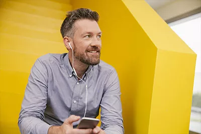 Jeune professionnel au téléphone, à l’écoute de suggestions professionnelles d’un collègue.